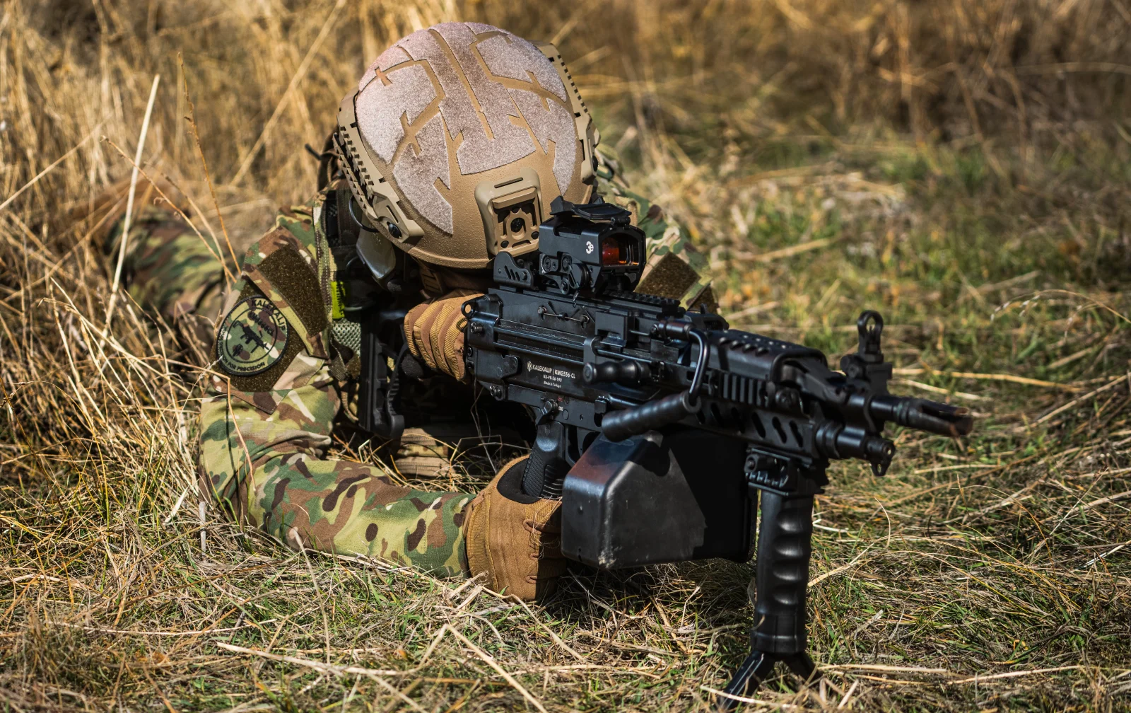KMG556CL ile prone pozisyonda mevzilenmiş asker, çim arazi