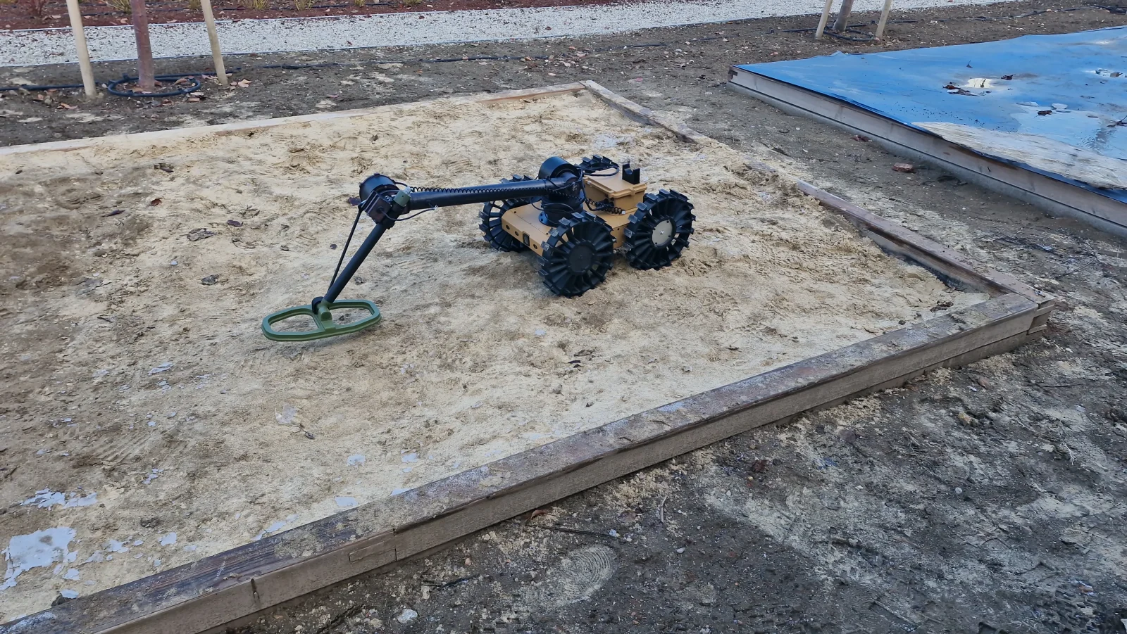 Merob 5 Açık arazide tekerlekli kara robotu üzerine monte edilmiş MEROB mayın tespit sistemi, kolun ucunda oval dedektör başlığı toprağa temas ediyor