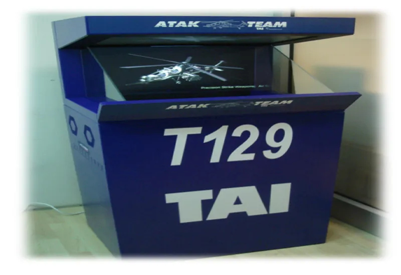 Qué es HoloTable: el cajón de arena holográfico de SimBT 5 Cabina de visualización holográfica rotulada ATAK TEAM y T129 TAI con la imagen de un helicóptero que parece suspendido en el aire